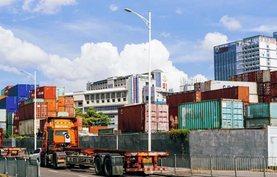 Imagem de caminhões carregados e contêineres em um porto industrial.