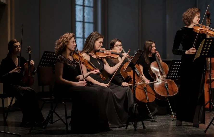 O que é música de câmara e como começar a ouvir Pequeno grupo de músicos tocando instrumentos de corda em um recital de música de câmara